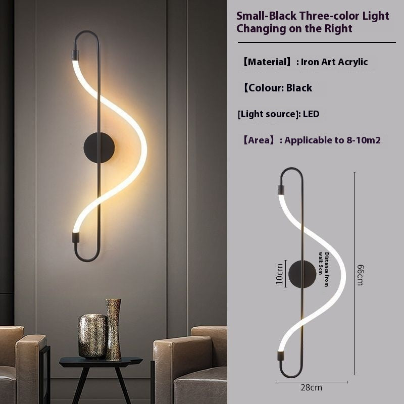S-shaped LED wall sconce in matte black with a glowing warm white light, shown mounted on a gray wall in a modern living room setting, alongside a technical specification and dimension diagram on the right.
