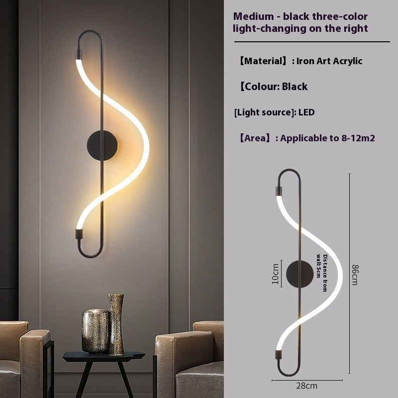 A modern wall-mounted LED light fixture with a black curved frame and a glowing white S-shaped light tube, shown installed on a gray wall in a living room setting. The right side includes a technical diagram with dimensions (86 cm height, 28 cm width, 10 cm distance) and product details text: medium size, black three-color light-changing, material iron acrylic, color black.