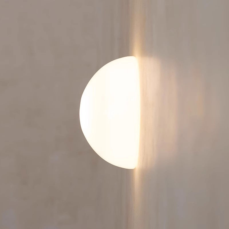 Round white light fixture on a textured wall