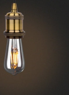 Vintage-style light bulb with brass fitting on a dark background