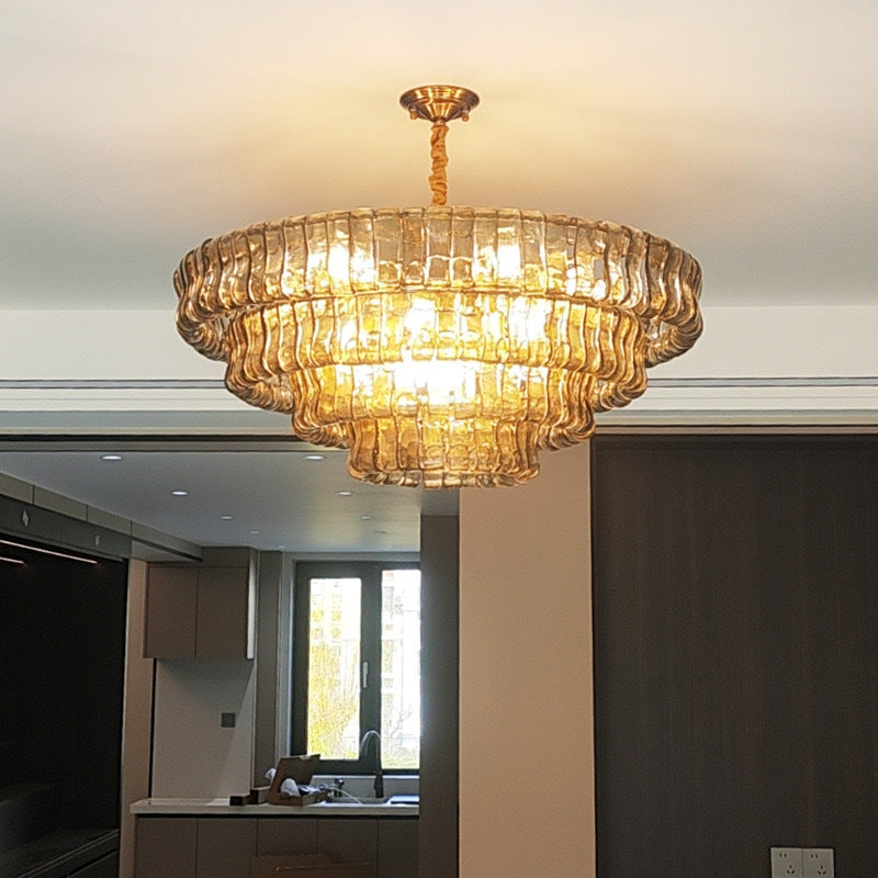 Gold chandelier hanging in a room with a kitchen in the background