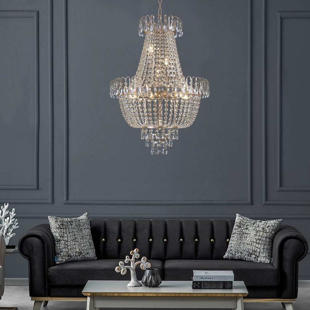 Chandelier hanging above a dark gray sofa with decorative pillows in a room with gray walls.