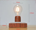 Wooden base with levitating light bulb on a gray background