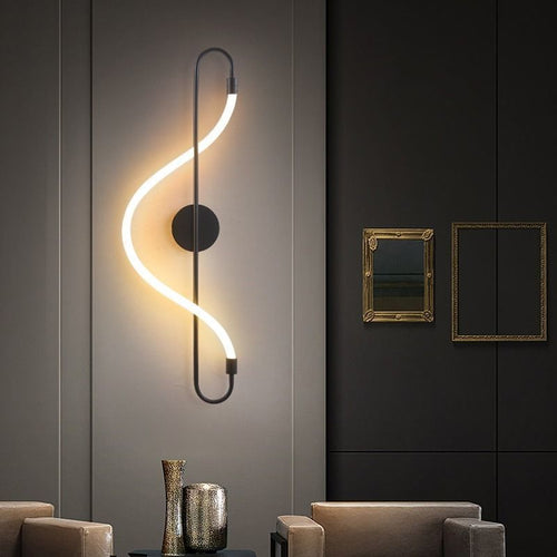 Modern wall light fixture in a stylish interior setting with a dark wall and framed mirrors.