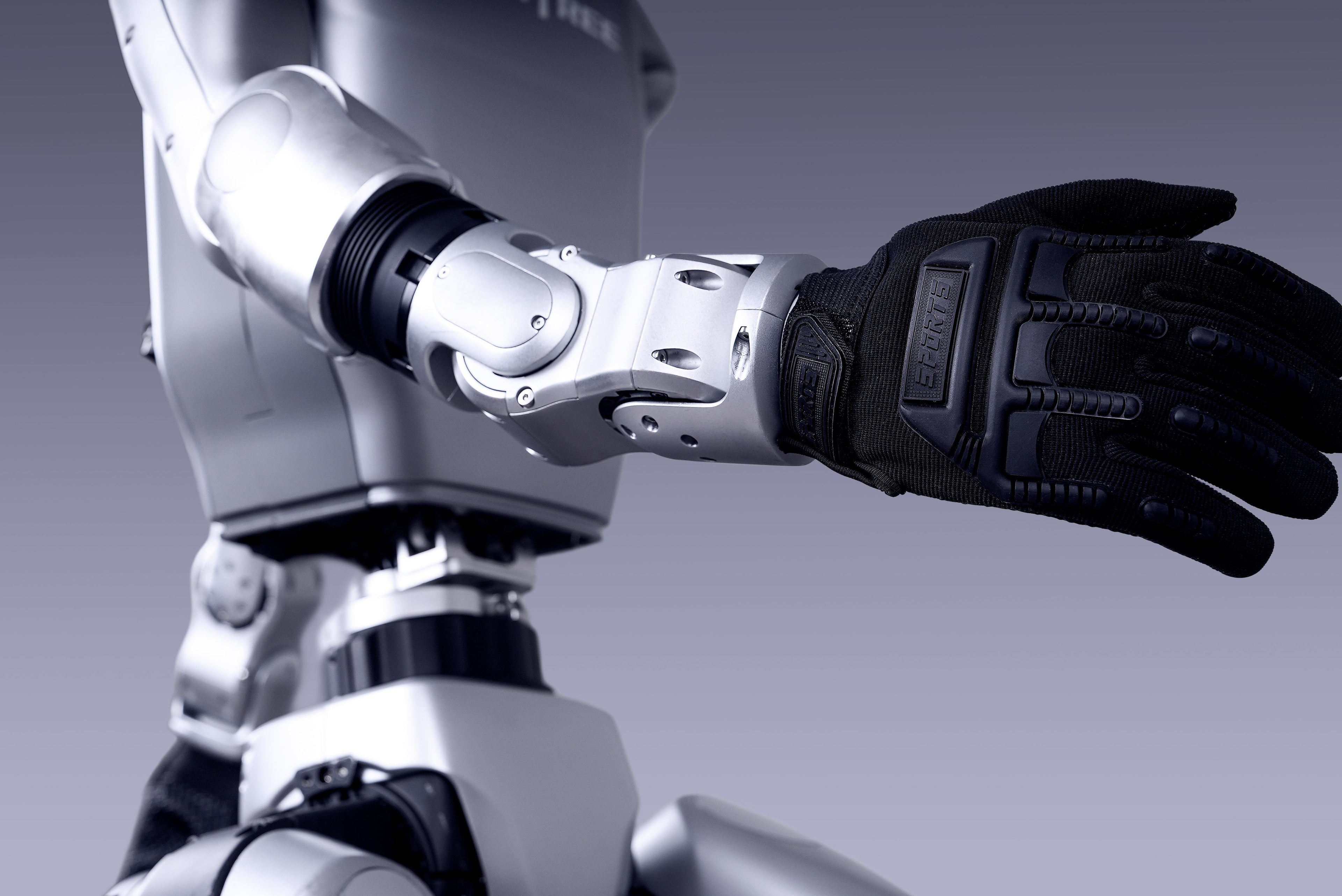 Robot hand with a black glove on a gray background