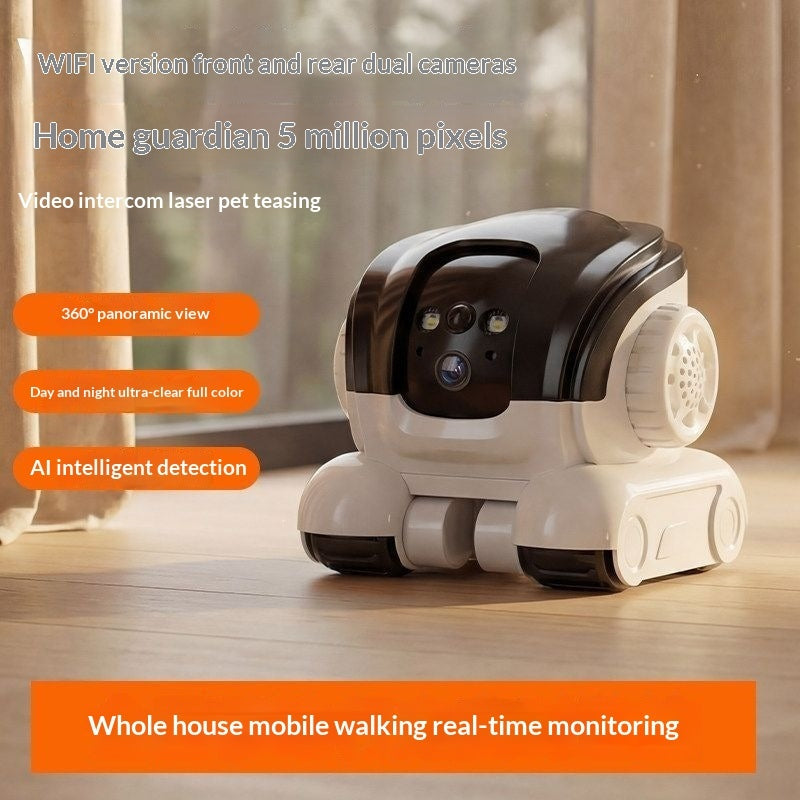 A small white and black robotic pet camera sits on a wooden floor in a home interior. The product has dual camera lenses on the front, side vents, and a rounded wheeled base.